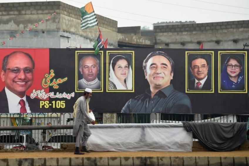 A man walks past an election banner displaying Bilawal Bhutto Zardari (C), chairman of Pakistan Peoples Party (PPP), along a street in Karachi on February 4, 2024, ahead of the upcoming general election