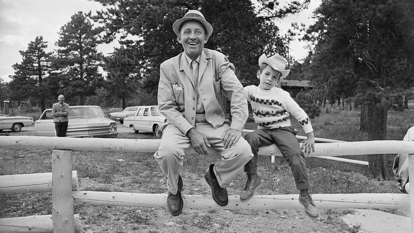 Bing Crpsby smiling in a suit sitting next to Harry Crosby wearing a cowboy hat