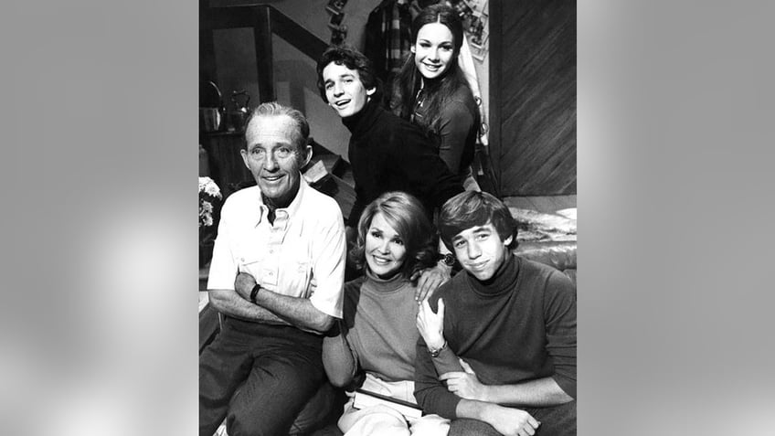 The Crosby family sitting together for a black and white portrait and smiling