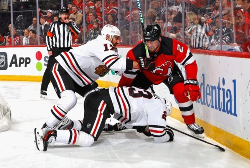 Nick Foligno and Philipp Kurashev of the NHL's Chicago Blackhawks go after Brendan Smith of the New Jersey Devils during the first period for his check on Chicago's Connor Bedard