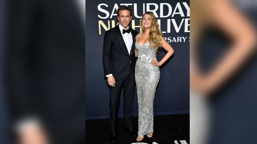 Ryan Reynolds wears a suit next to Blake Lively on red carpet.