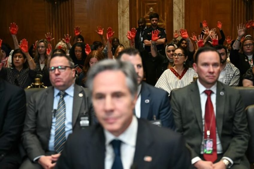 Pro-Palestinian demonstrators hold up painted hands in protest as US Secretary of State An