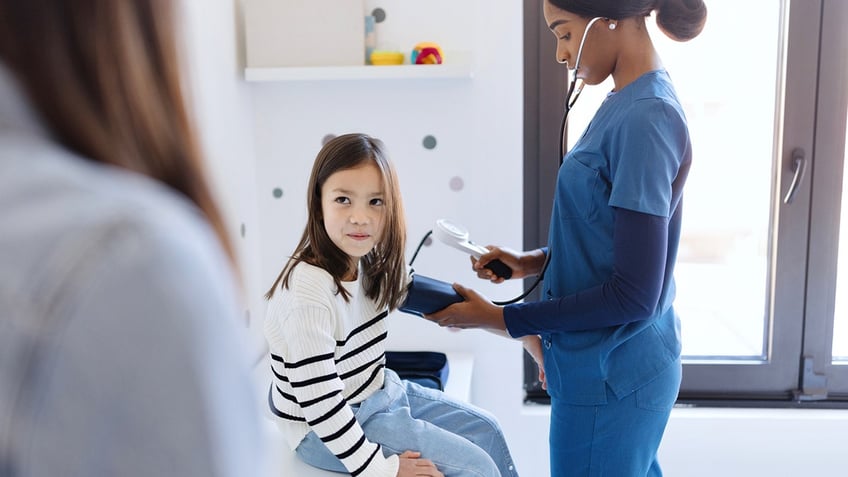 Nurse measuring blood pressure of a little girl