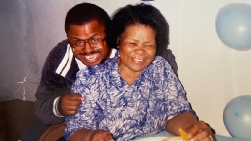 Michael Beverly smiling and holding his mother.