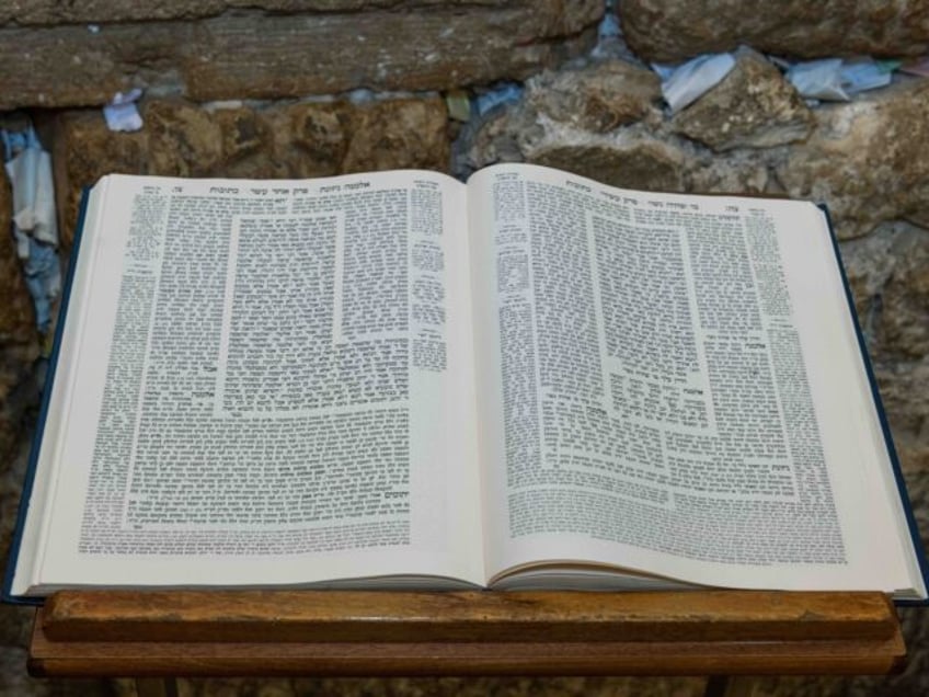 A Talmud open to the text from the tractate Ketubot rests on a prayer stand in front of th