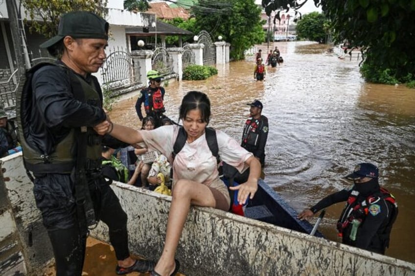 Rescuers in boats carry schoolchildren and residents to safety after flooding in the north