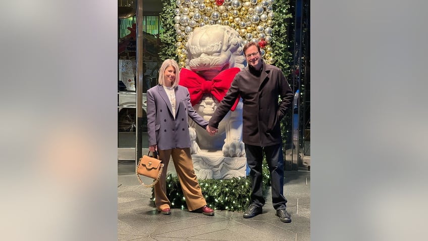 Kelly Rizzo and Bob Saget wearing winter outerwear while holding hands outdoors