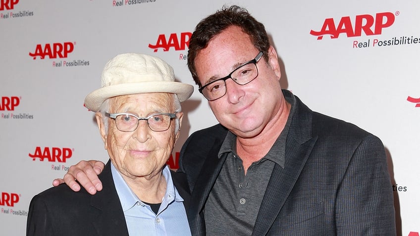 A closeup of Bob Saget embracing Norman Lear