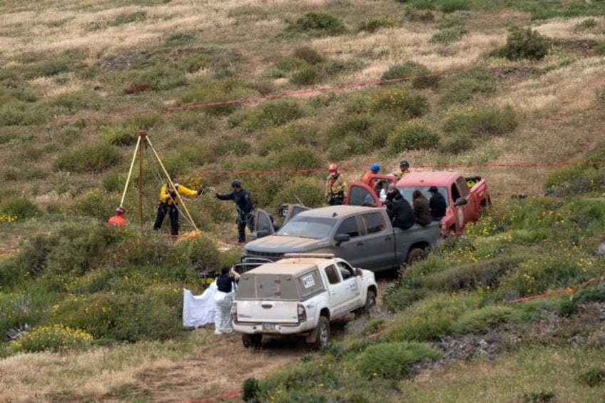 Rescuers are seen working at a clifftop shaft where bodies believed to be those of three m