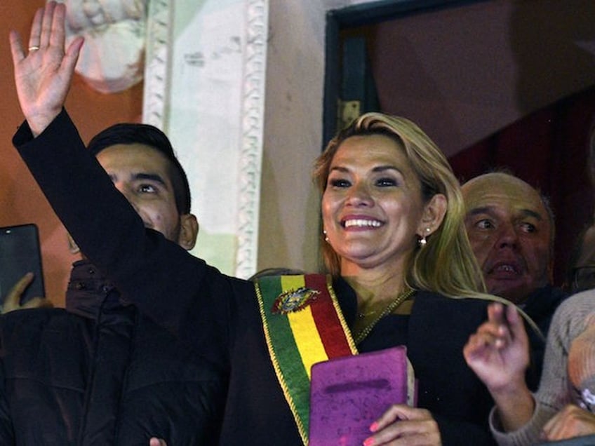 TOPSHOT - Deputy Senate speaker Jeanine Anez, waves from the balcony of the Quemado Palace in La Paz after proclaiming herself the country's new interim president in a session of Congress that failed to reach a quorum, on November 12, 2019. - Bolivia's Evo Morales jetted off to exile in Mexico on Tuesday, leaving behind a country in turmoil after his abrupt resignation as president. The country has been hit by weeks of unrest amid violent protests following Morales' contested re-election. (Photo by Aizar RALDES / AFP) (Photo by AIZAR RALDES/AFP via Getty Images)