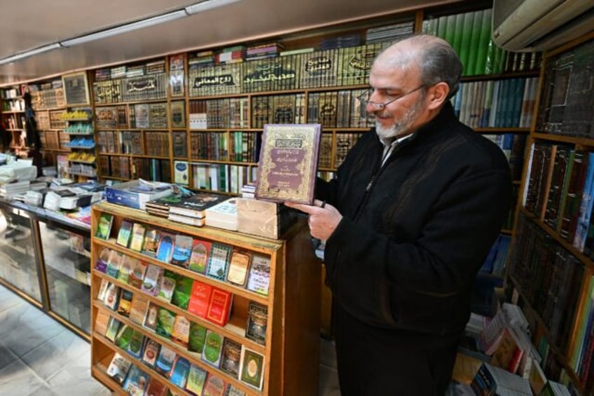 A bookseller shows a volume that was reportedly banned during the rule of Syria's ousted p