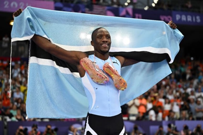 Letsile Tebogo poses with the Botswana flag after a stunning run to win 200m gold at the P