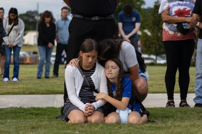 A mother and her children bow their heads in prayer at a vigil for the victims of the Apal