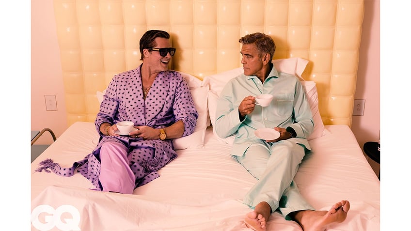 Brad Pitt and George Clooney sit on a bed together