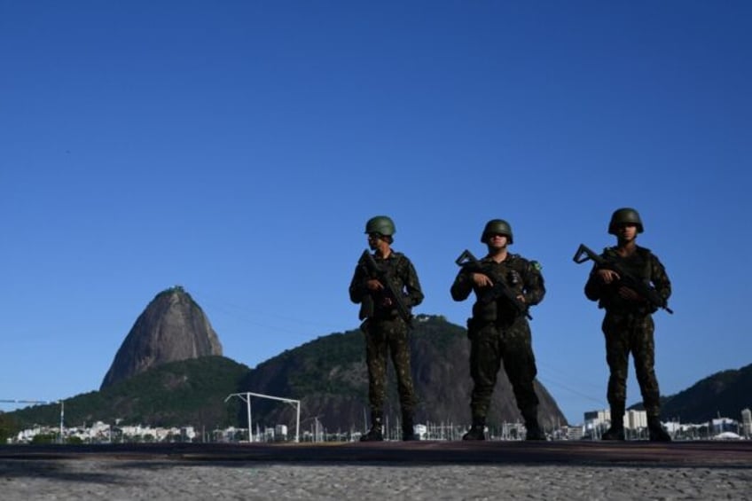 Brazilian army soldiers stand guard on Botafogo beach with the Sugar Loaf mountain in the