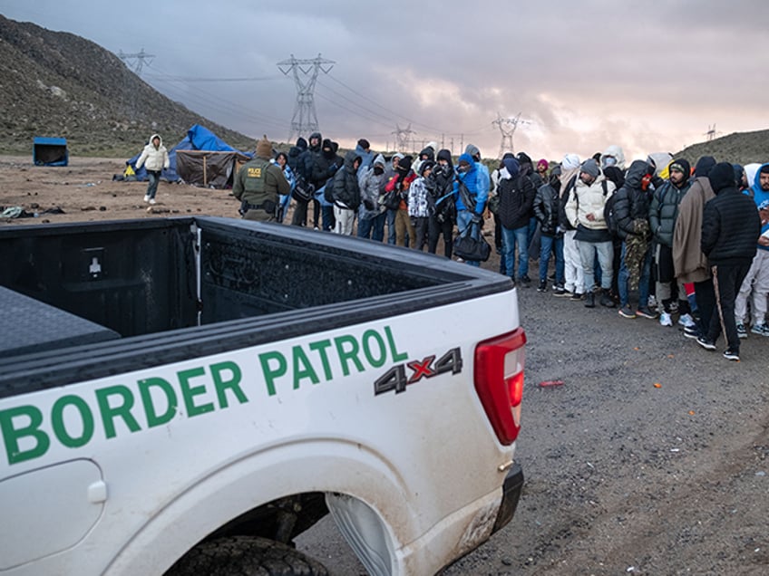 Asylum seekers wait in line to be processed by the Border Patrol at a makeshift camp near