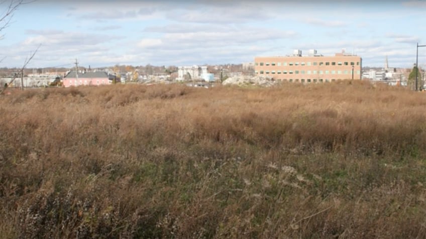 Empty field with buildings in the distance