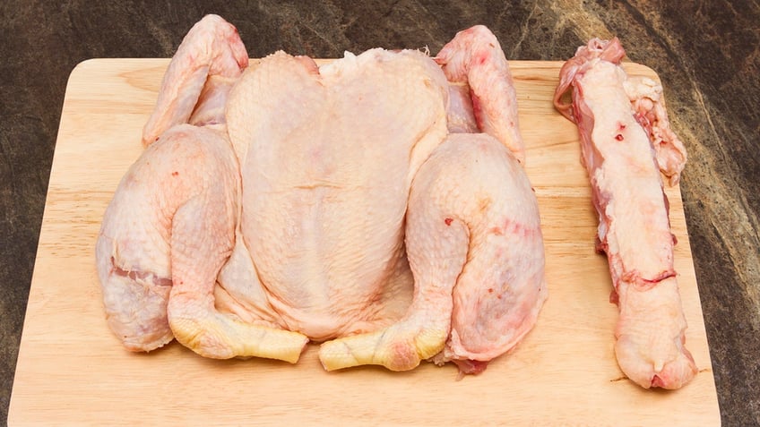 A spatchcocked chicken on a wooden cutting board.