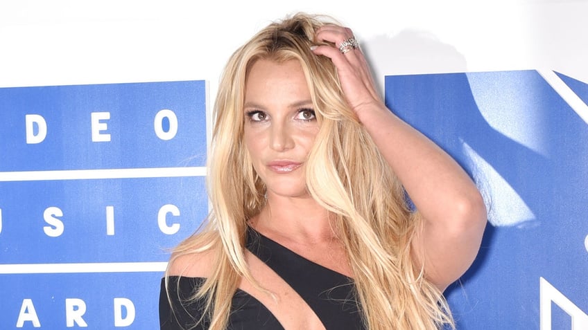 Singer Britney Spears wears black cut out dress on red carpet.