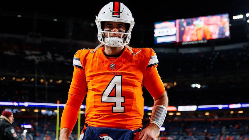 Jarrett Stidham walks on the football field before a game