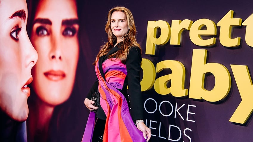 Brooke Shields in a striped pink, red, purple orange dress with black sleeves on the carpet for her documentary premiere