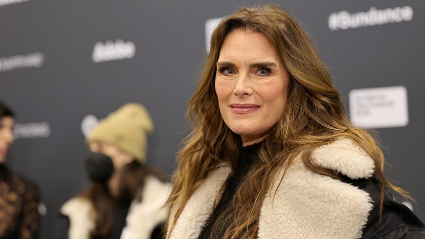 Brooke Shields soft smiles on the carpet in Utah wearing a shearling jacket