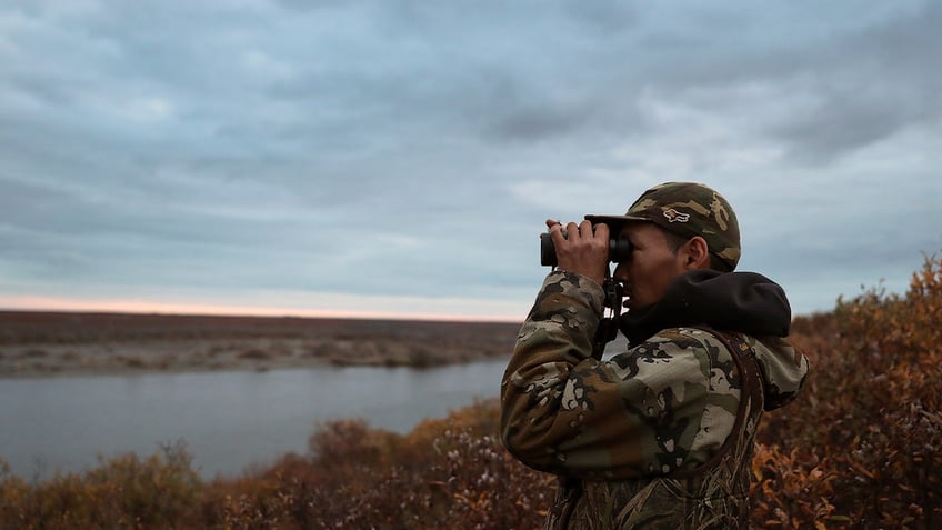 Hunter looks through binoculars