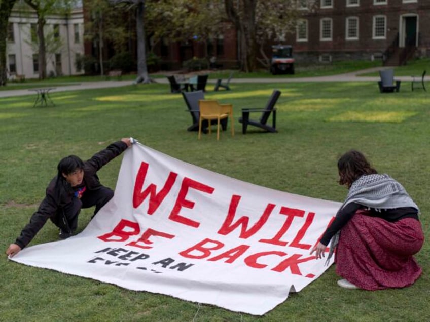 Demonstrators unfurl a banner on a lawn after an encampment protesting the Israel-Hamas wa