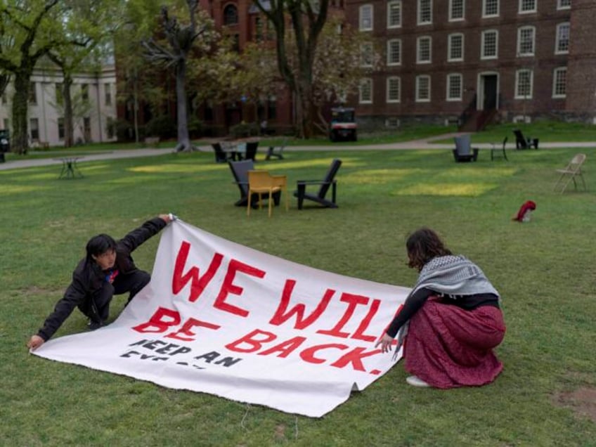 Demonstrators unfurl a banner on a lawn after an encampment protesting the Israel-Hamas wa