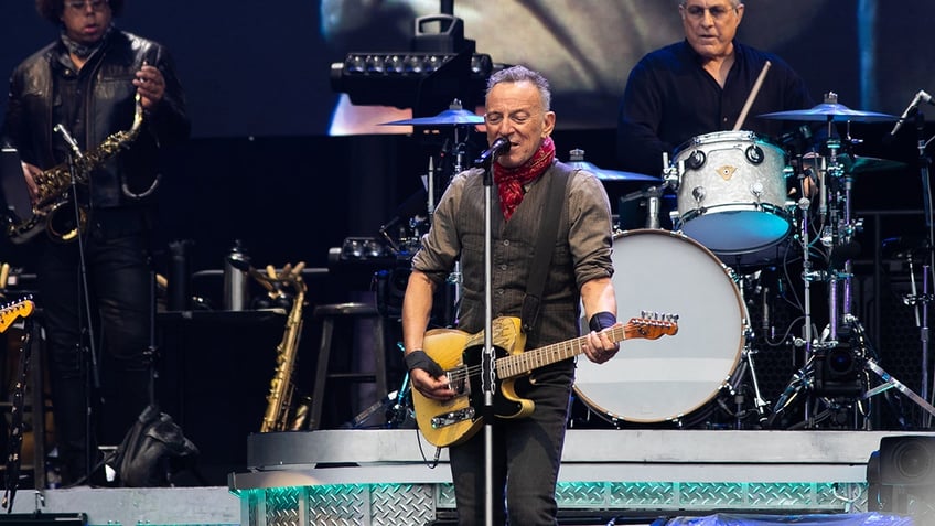 Bruce Springsteen singing into microphone and playing guitar