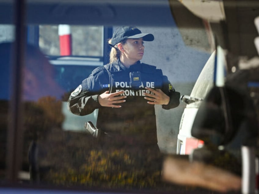 A picture taken on October 29, 2022, shows a Romanian border police officer inspecting a car on the Romania-Serbia border checkpoint at the Iron Gates bridge over Danube river near the city of Drobeta-Turnu Severin. - Europol announced on November 4, 2022 the arrest of 382 people in late October …