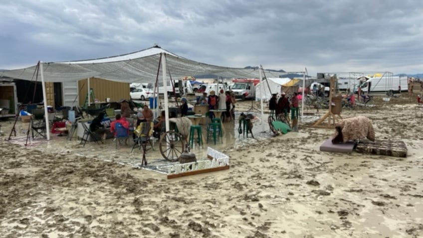 burning man festival attendee treks through ankle deep mud to escape our only option to get out