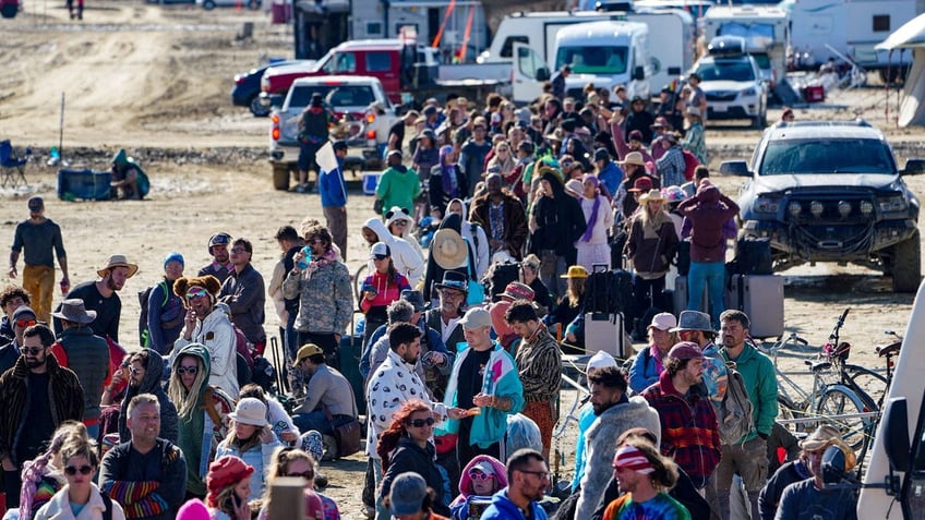 burning man festival attendee treks through ankle deep mud to escape our only option to get out