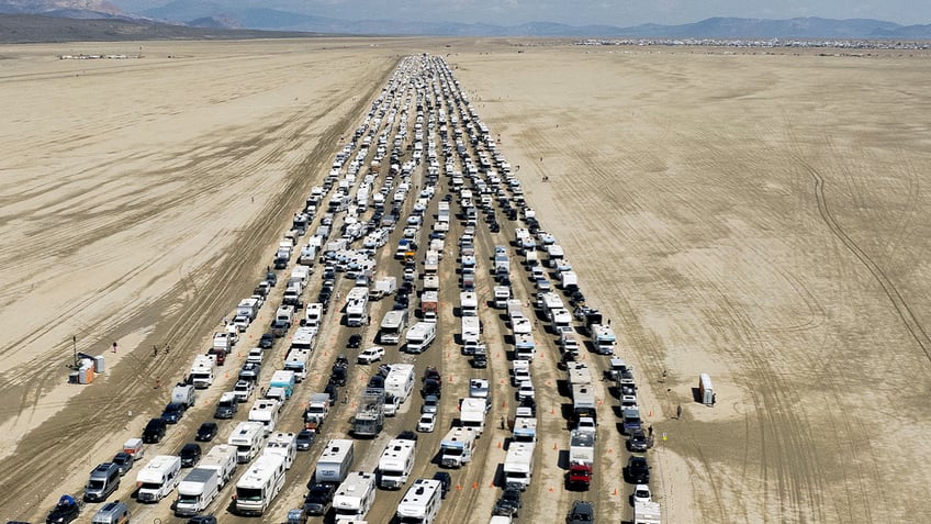 burning man festival attendee treks through ankle deep mud to escape our only option to get out