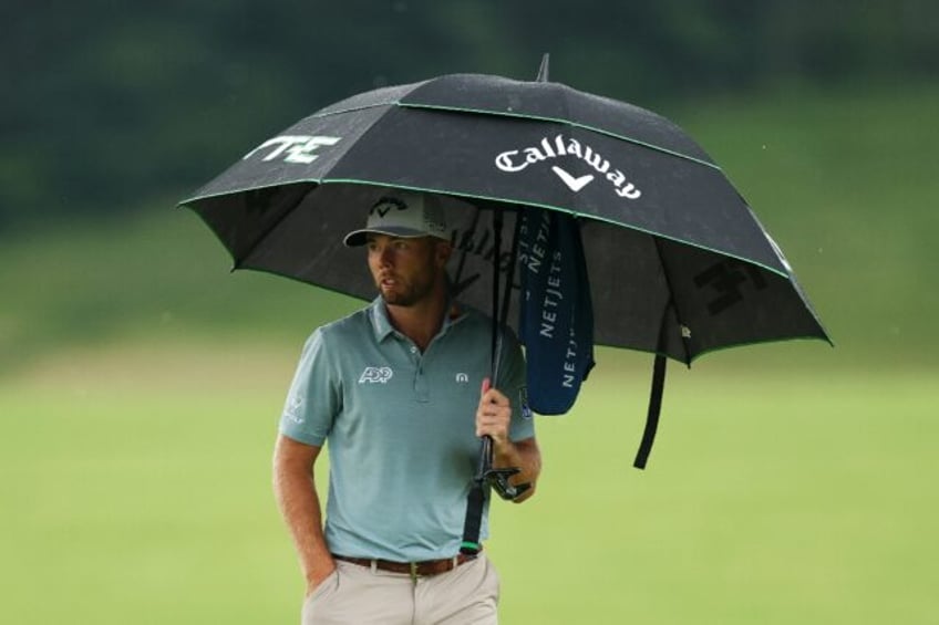 US Open leader Sam Burns of the United States waited under his umbrella as heavy rain halt