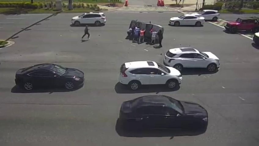 Group of people help flip over car on intersection