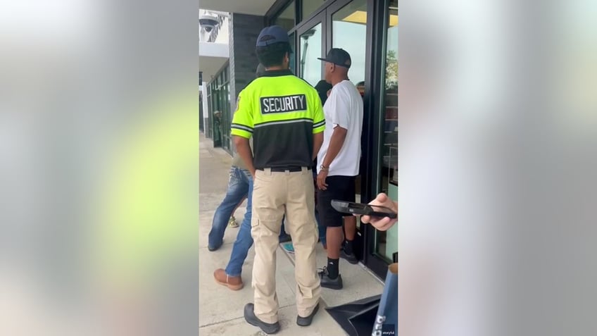 bystanders holding front door of store shut