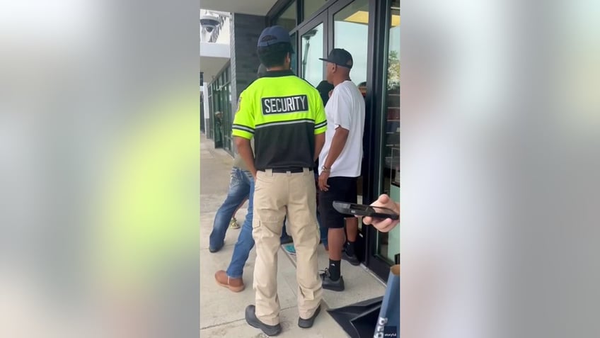 bystanders holding front door of store shut