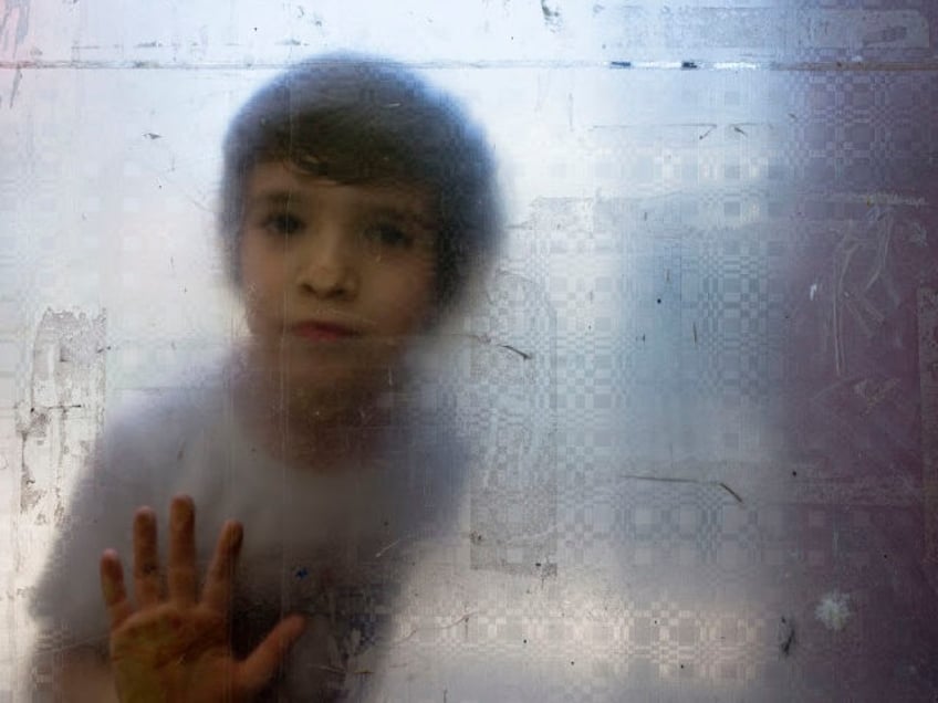 In this Dec.13, 2018 photo, Laura, a transgender girl, looks from behind a glass door during recess at the Amaranta Gomez school in Santiago, Chile.