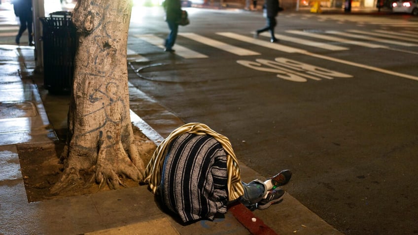 A homeless person sleeps on a sidewalk in Los Angeles, Wednesday, Dec. 14, 2022.