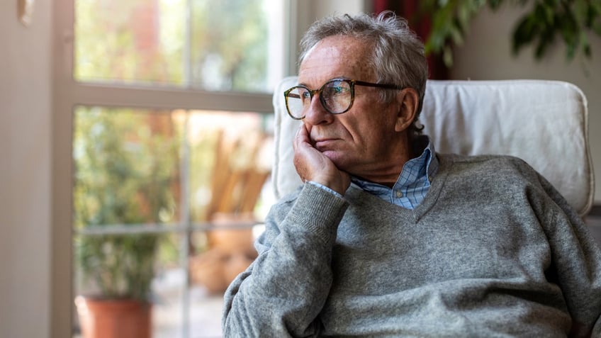 Senior man looking out of window at home