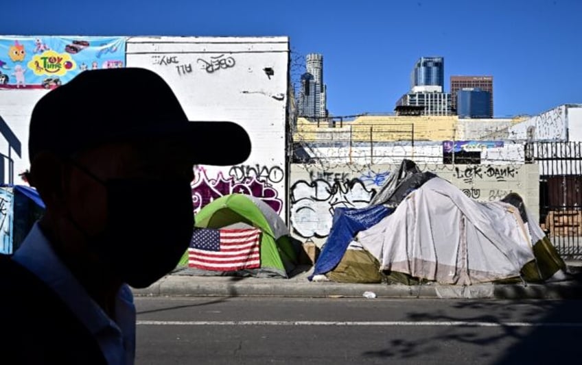 A man walks past tents housing the homeless people in Los Angeles, California