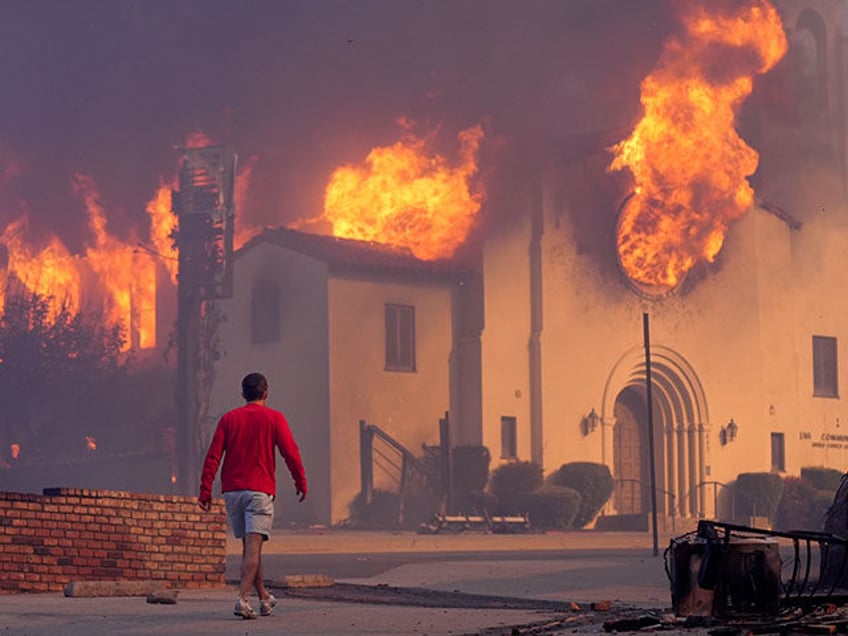 A man walks in front of the burning Altadena Community Church, Wednesday, Jan. 8, 2025, in