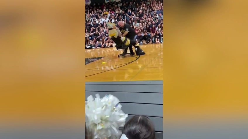 High school principal Robert Nunes dances with mascot