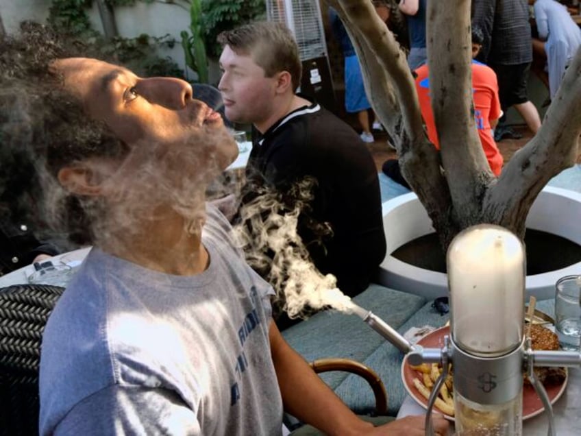 A man takes a puff from a marijuana pipe joined his girlfriend Vannessa Hursey during his