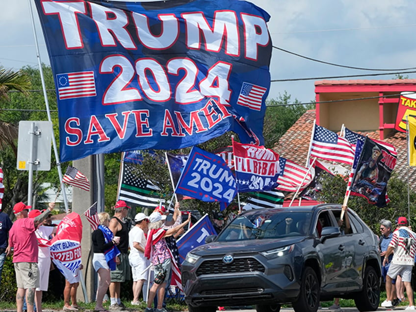 Supporters of former President Donald Trump chant and wave flags at a rally, Monday, April