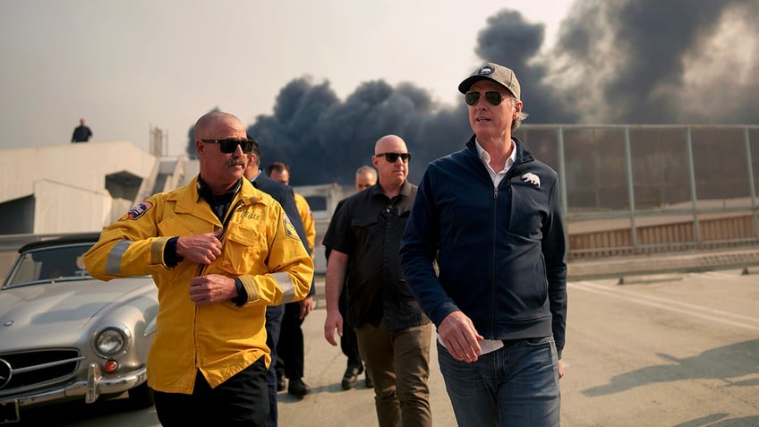 California Governor Gavin Newsom (R) tours the downtown business district of Pacific Palisades as the Palisades Fire continues to burn on January 8, 2025, in Los Angeles, California.