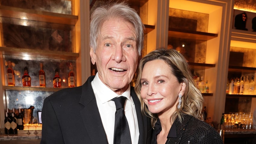 Harrison Ford looks excited taking a picture with his wife Calista Flockhart, both in black