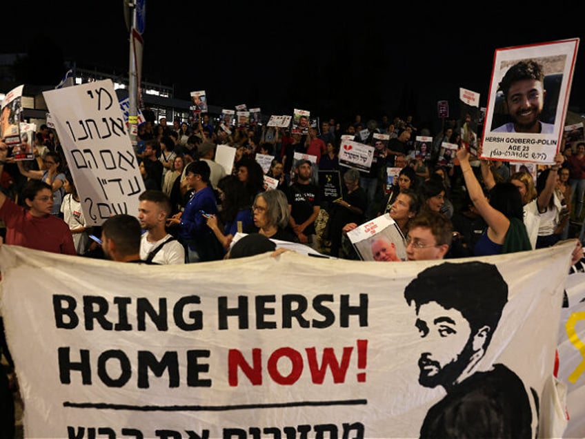 Relatives and supporters raise placards and deploy a banner bearing portraits of Israeli h