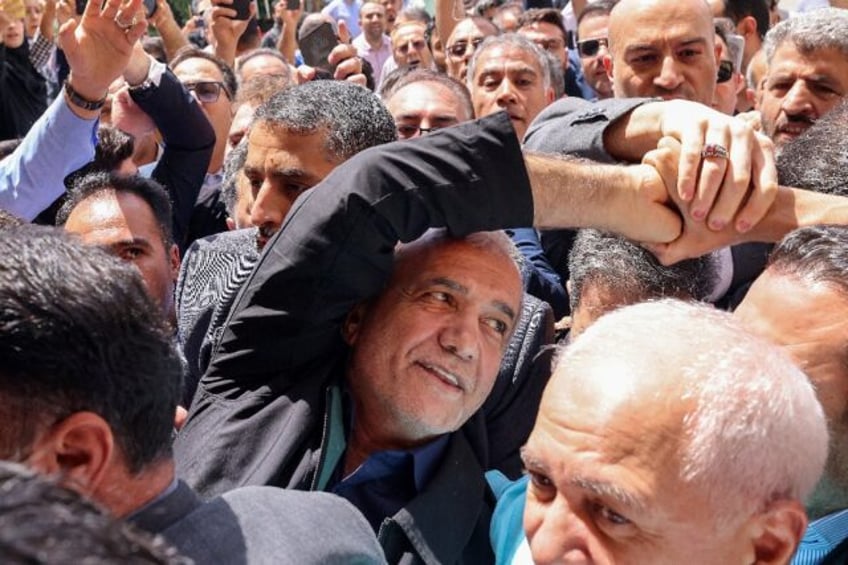 Iranian reformist presidential candidate Masoud Pezeshkian (C) greets supporters outside a